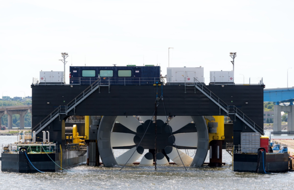 A marine hydrokinetic device mounted in a barge, being moved into position on the water.